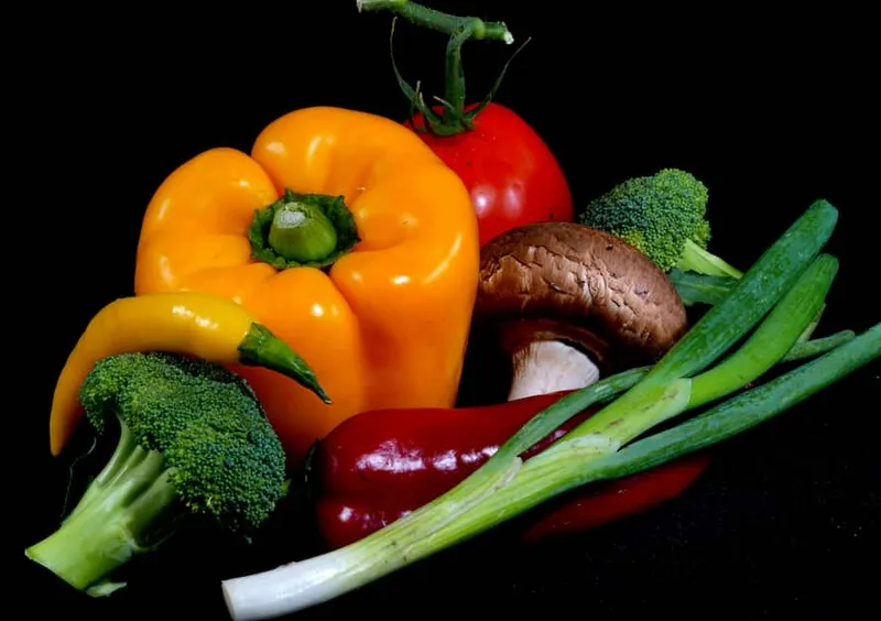 Best vegetables for eyes like broccoli, peppers and greens arranged together on a dark background.