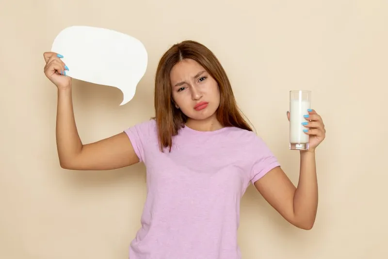 Is Milk Bad for Kidney Stones question shown by a woman holding a glass of milk with a confused expression
