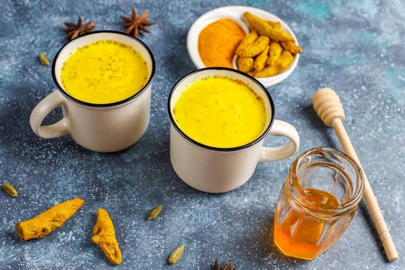 Warm turmeric milk served with raw turmeric, honey, and spices — a natural Ayurvedic option for those asking what is the best drink for fatty liver.