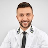 Young male doctor in white coat smiling and ready to assist patients